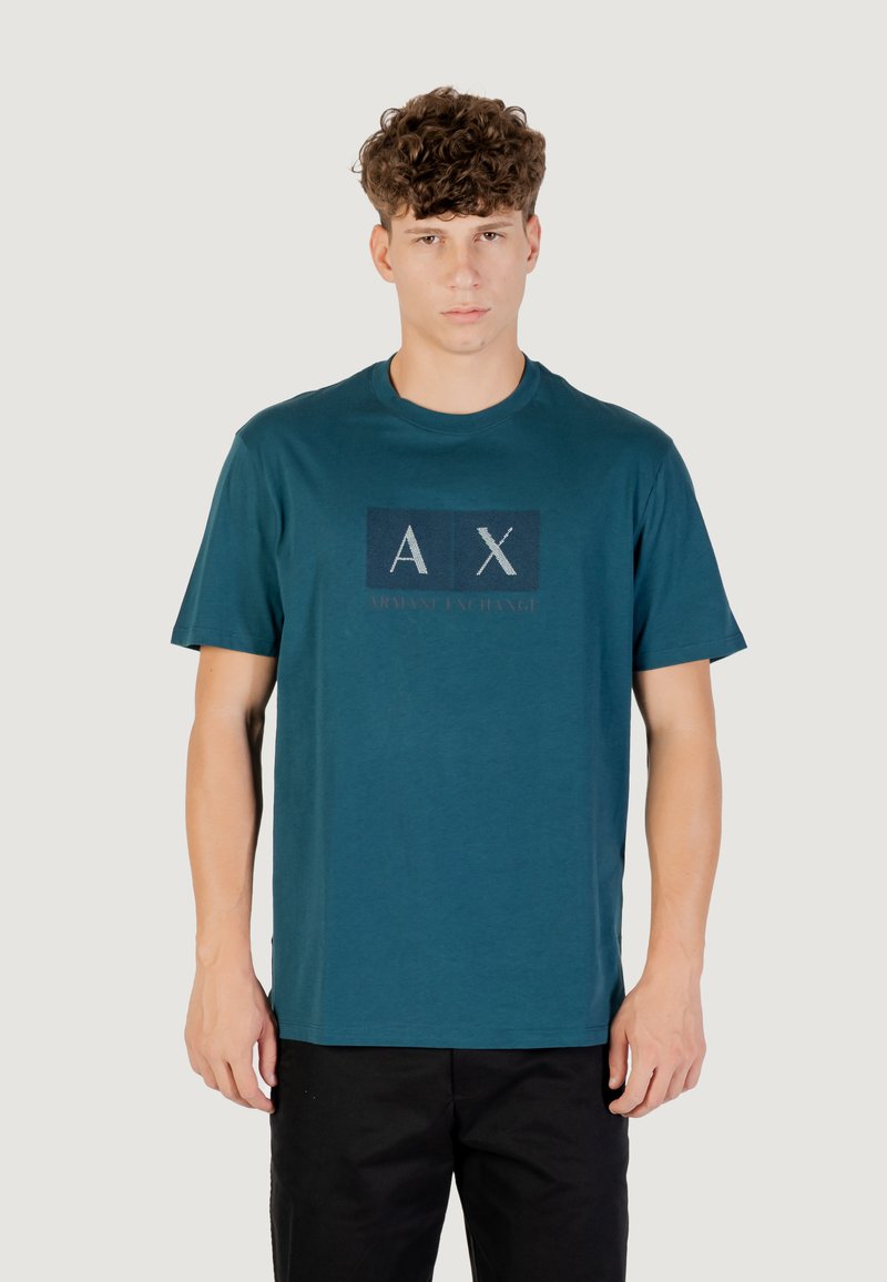 T-shirt en coton teal avec des manches courtes, arborant un design de logo rectangulaire en bleu foncé et blanc, affichant "AX ARMANI EXCHANGE."