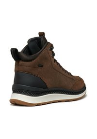 Zapatilla alta de cuero marrón con acentos negros, talón texturizado y una mediasuela blanca acolchada. Cuenta con diseño de cordones y pestaña en el bucle.