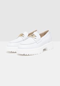 Mocassins blancs en matériau synthétique, avec une semelle épaisse, des accents en métal doré, et une texture lisse avec des détails cousus.