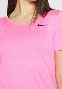 Rosa idrottströja med rundad halsringning och korta ärmar. Har en subtil textur och en svart Nike-logotyp på övre vänstra sidan.