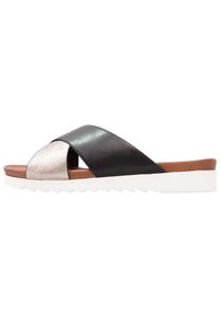 Schwarze und silberne Leder-Sandalen mit einem Kreuzriemen-Design, einer braunen Fußbett und einer weißen Keilsohle mit Zickzack-Muster.