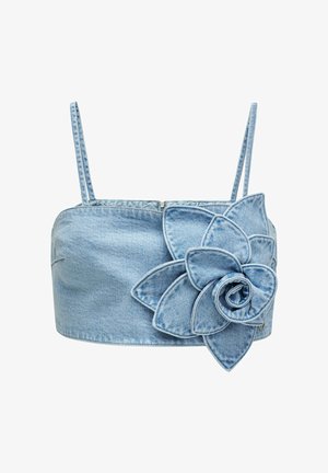 Crop top en denim bleu clair avec fines bretelles et grand détail de fleur en tissu superposé sur le côté droit devant.