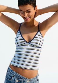 Tílko na ramínka s horizontálními pruhy v modré, žluté a námořnické barvě. Měkká tkanina s přiléhavým střihem a hlubokým výstřihem do V.