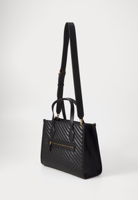 Sac à main noir avec motif texturé diagonal, double poignées supérieures et bandoulière amovible. Comprend une poche zippée à l'avant et des accents dorés.