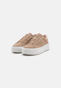 Beige Wildlederschuhe mit einer weißen Gummiplattformsohle, ausgestattet mit runden Schnürsenkeln, Metallösen und einer strukturierten Zehenkappe.