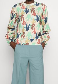 Sweatshirt multicolore avec motif de mains, tissu doux, col ras du cou et poignets élastiqués, accompagné d'un pantalon bleu clair sur mesure.