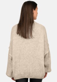 Maglione oversize beige in maglia con un motivo testurizzato e spalle scese. Polsini e orlo a coste, con una vestibilità rilassata.