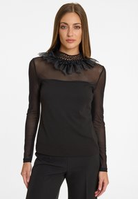 Schwarzes Langarmoberteil mit durchsichtigen Netzärmeln und einem gerafften Spitzenhalsausschnitt. Der Körper hat ein glattes, eng anliegendes Design.