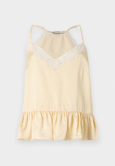 Camisole en satin crème avec bordure en dentelle blanche au niveau de l'encolure, bretelles spaghetti réglables et ourlet à volants.