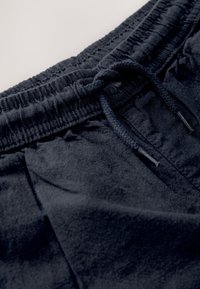 Tengerészkék pamut melegítőnadrág elasztikus derékpánttal, állítható húzózsinórral, puha tapintású, sima felületű részletekkel.