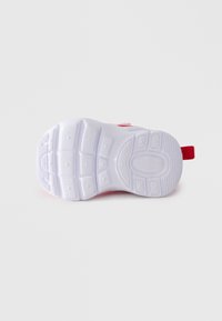 Gumeni dio bijele tenisice s crvenim detaljima, prikazuje uzorak gaznoga sloja i Nike Air Max oznaku, na jednostavnoj bijeloj pozadini.