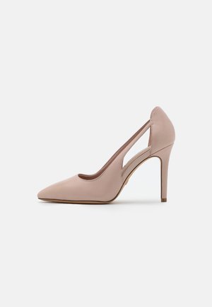 Nude spitse teenveter met een uitgesneden zijkant en slanke stilettodetails op een witte achtergrond.