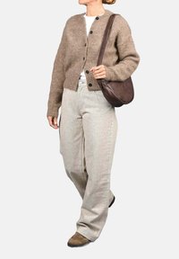 Cárdigan marrón de punto con cierre de botones, combinado con pantalones de pierna ancha en gris claro y un bolso de hombro de cuero marrón.