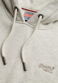 Lichtgrijze hoodie van zacht materiaal, met een trekkoordkap, geborduurd logo en metalen uiteinden op de trekkoorden.