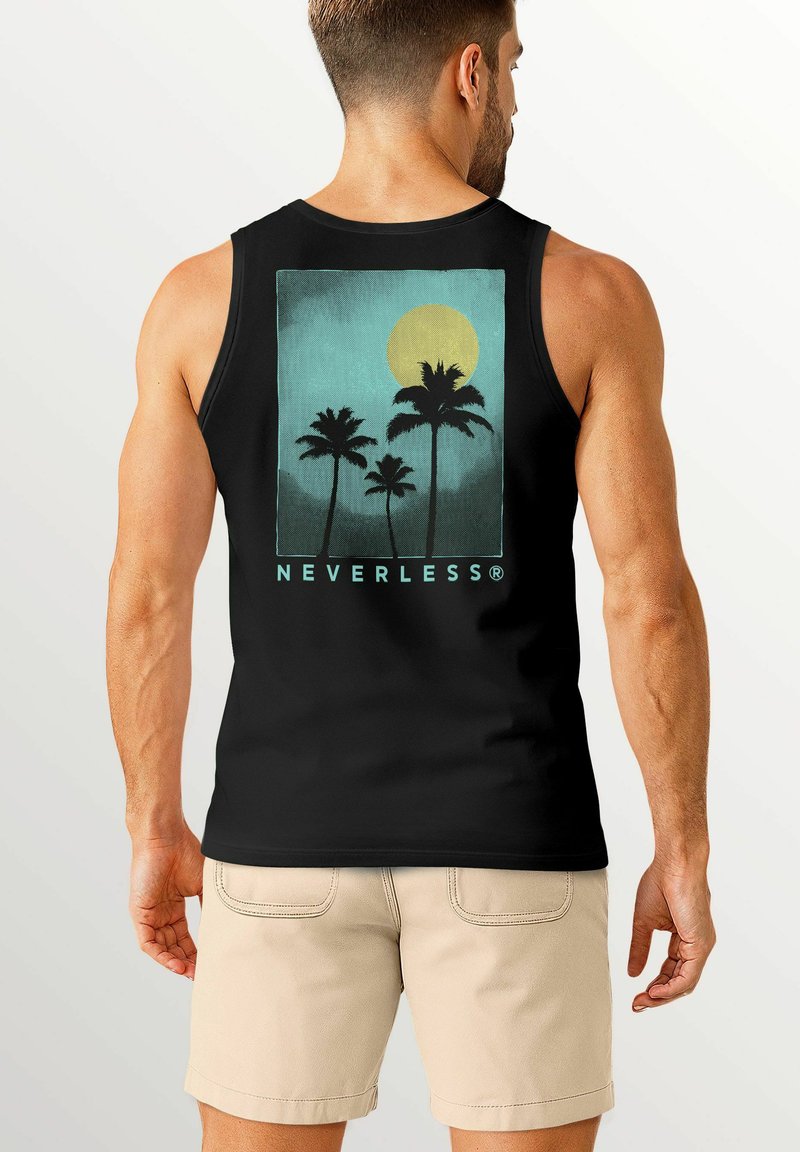 Ein Mann steht mit dem Rücken zur Kamera und trägt ein schwarzes Tanktop, auf dem ein Grafik von Palmen und einer Sonne zu sehen ist. Dazu trägt er Shorts.