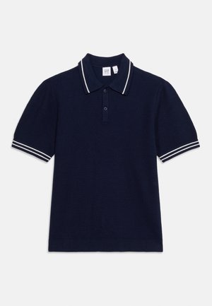 Κοντομάνικο polo μπλουζάκι σε ναυτικό μπλε με λευκές διπλές ρίγες στον γιακά και τις μανσέτες, με κούμπωμα δύο κουμπιών, τοποθετημένο επίπεδα σε λευκό φόντο.