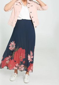 Fladdrande marinblå plisserad kjol med blommönster i rosa och röd, kombinerad med en vit topp och en ljusrosa jeansjacka, avslutad med vita sneakers.