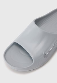 Sive sandale za plažu izrađene od glatke plastike. Dizajn otvorenih prstiju s zakrivljenim gornjim dijelom i suptilnim reljefnim logom sa strane.