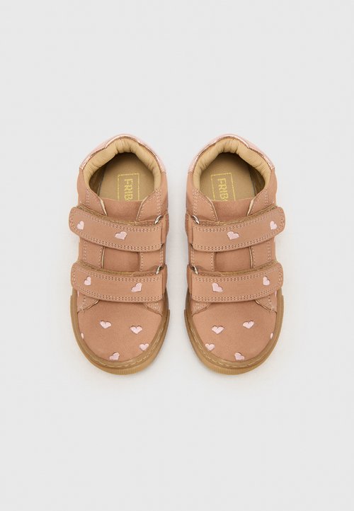 Baskets en velcro marron avec des motifs de cœurs roses, texture ressemblant à du daim, bout rond et semelle en caoutchouc. Intérieur doublé pour plus de confort.
