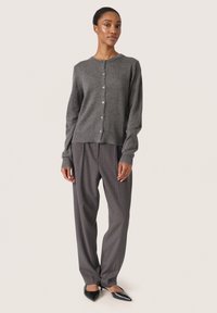 Cardigan gri tricotat cu mâneci lungi și guler rotund, având nasturi mici și manșete cu nervuri, asortat cu pantaloni gri cu dungi fine.