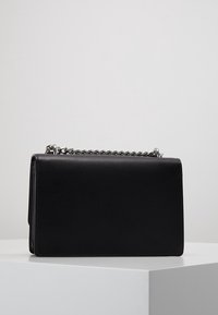 Czarna skórzana torebka w eleganckim, prostokątnym kształcie, z srebrnym łańcuszkiem i minimalistycznym designem, bez widocznych logo czy ozdób.