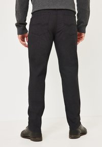 Dark gray denim trousers with a slim fit, featuring stitched back pockets, subtle vertical texture, and paired with dark shoes.