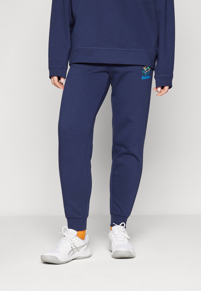 Marineblå joggebukser i myk tekstil, med elastisk midje, ribbede mansjetter og Lotto-logo i turkis på venstre lår.