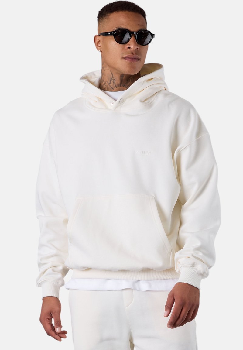 Hoodie blanc avec une poche avant, un col ajustable et des poignets côtelés. Matière en mélange de coton douce. Assorti avec un pantalon clair.