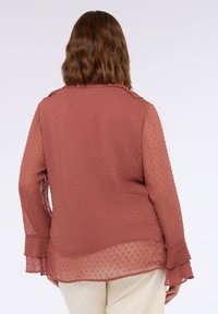 Lange mouwen, doorschijnende blouse in roestkleur met een gestructureerd stippenpatroon, kraag en gerimpelde manchetten.
