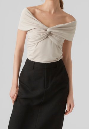 Kermanvalkoinen olkapäät paljastava paita, jossa edessä nyöritysidetailit, yhdistetty korkeavyötäröiseen mustaan hameeseen. Sileä kangas ja vartalonmyötäinen malli.