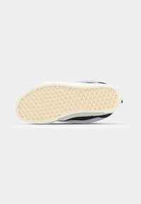 Svart sneakersole med en teksturert hvit gummisåle og lavendelakenter. Har en glatt overflate og et lavprofildesign.