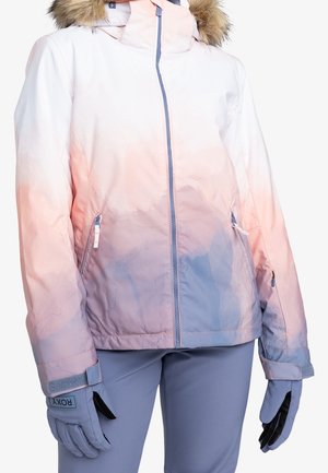 Femme portant une veste d’hiver rose pastel et violette avec capuche en fourrure et gants et pantalon violets assortis, vue de la moitié du torse vers le bas.