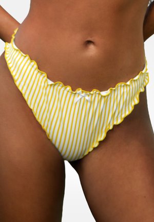 Frau trägt weiße Bikinihose mit dünnen vertikalen gelben Streifen und gerafften Rändern, zeigt Bauchbereich und obere Oberschenkel.