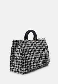 Torebka z tkaniny typu tweed w czarno-białym wzorze pepitki o wyraźnej formie i czarnym skórzanym uchwycie. Teksturowana powierzchnia, brak widocznych elementów metalowych.