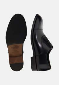 Scarpe eleganti da uomo in pelle nera con finitura liscia, caratterizzate da un design con lacci, punta arrotondata e una soletta interna in pelle marrone a contrasto.