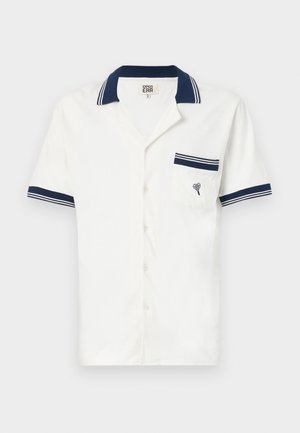 Rövidujjú, fehér, galléros ing, sötétkék csíkokkal a galléron és az ujjakon, mellkasi zsebében szív emblémával. Texturált anyag.