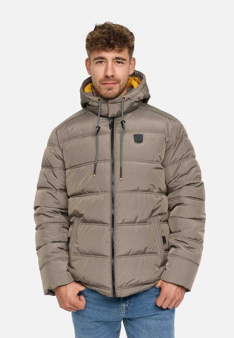 Polstret zip-jakke i dempet grå med en kontrastfarget gul hetteforing. Har elastiske snorene, sidelommer og et logo-patch.