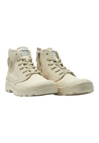 Stivali alti beige realizzati in tela con una suola di gomma texturizzata. Tra le caratteristiche ci sono i lacci, una cerniera laterale e un patch con logo sulla caviglia.
