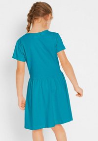 Robe turquoise à manches courtes avec un corsage ajusté et une jupe évasée, fabriquée en tissu en coton doux, présentant un col rond simple.