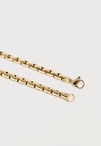 Κολιέ αλυσίδας σε χρυσό τόνο με ορθογώνιες συνδέσεις, διαθέτει κούμπωμα τύπου λόμπστερ στη μία άκρη και κρίκο στην άλλη, απλωμένο επίπεδα σε λευκή επιφάνεια.
