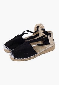Espadrillas nere in canvas con suole in juta, caratterizzate da cuciture bianche, dettagli in beige testurizzato e nastri neri legati alla caviglia.