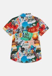 Chemise à manches courtes avec boutons, arborant un collage vibrante de plaques d'immatriculation colorées et de graphiques sur le thème des voyages sur un fond multicolore.