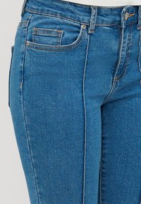Λιτές τζιν παντελόνες σε μέτριο μπλε με διακριτική φθορά, πέντε τσέπες, αντίθετο ράψιμο και ελαφριά ελαστικότητα για άνεση.