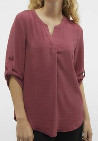 Blouse ample en V de couleur rose profond. Tissu léger et texturé avec des manches roulées et des accents de boutons.