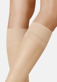 Beige, knielange Strümpfe mit glatter, transparenter Textur und einem breiten Bündchen, in das die Marke "KUNERT" am oberen Rand eingewebt ist.