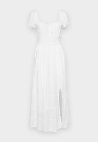 Vit långklänning ända ner till golvet med korta puffärmar, resårinfattad överdel, kjol i flera lager och slits i sidan. Tillverkad av lätt tyg.