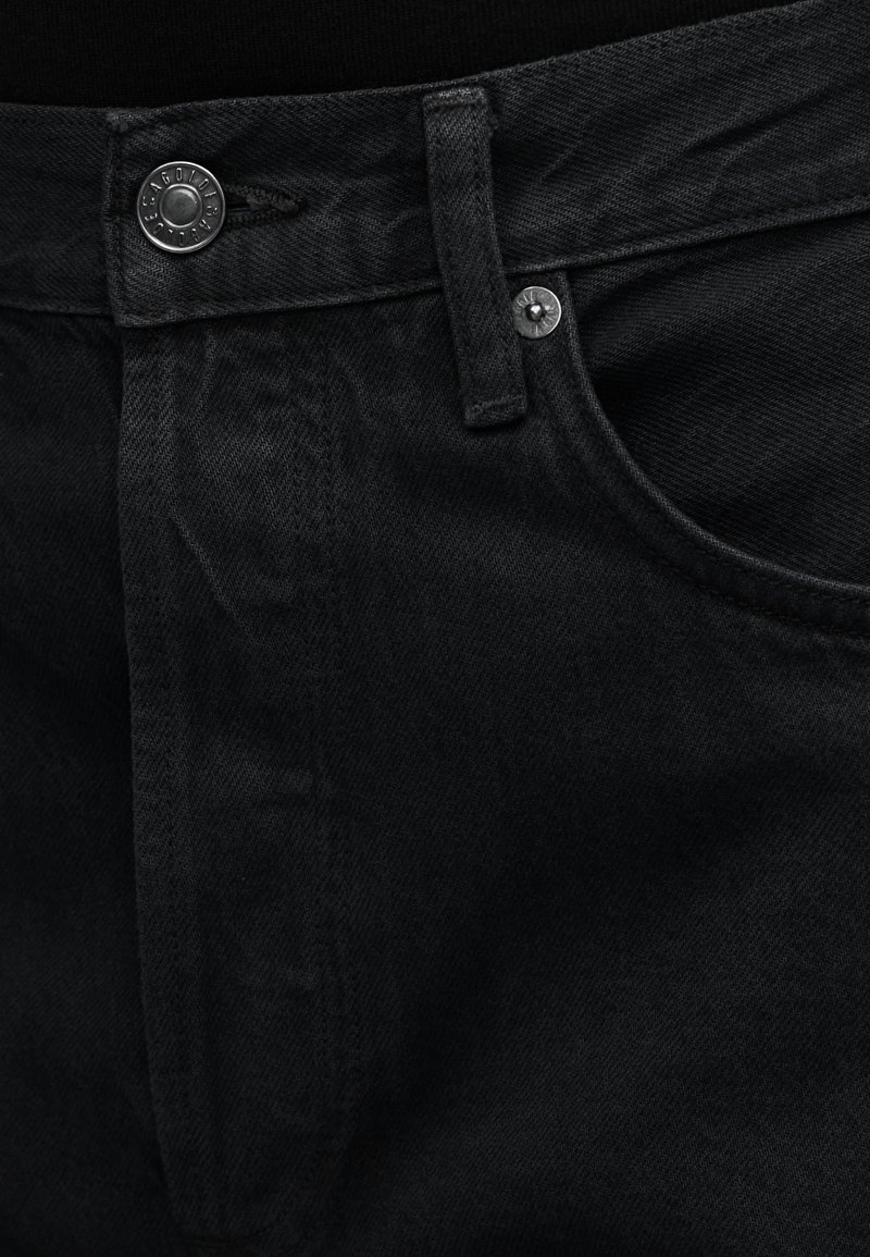 Jean en denim noir avec une fermeture à boutons, des poches avant et une coupe droite. La texture est lisse avec un léger détail de tissu.