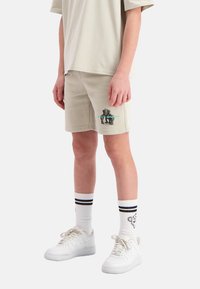Beige katoenen shorts met een olifantenafbeelding, gecombineerd met witte sneakers en gestreepte crew-sokken. Eenvoudig, casual ontwerp, knielang.