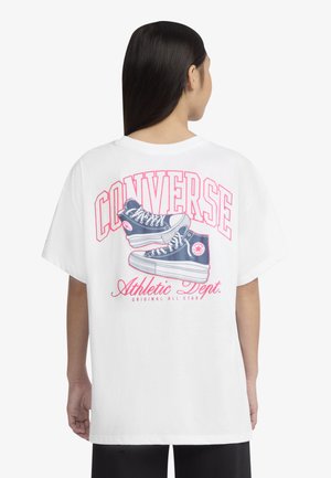 Hvid oversized t-shirt med grafik af blå sneakers, fed rød tekst "CONVERSE" og "Athletic Dept." på ryggen.