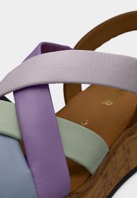 Σανδάλι με σταυρωτά λουριά από απαλό δέρμα σε αποχρώσεις λεβάντας, πράσινου και μπλε. Σόλα πλατφόρμα από φελλό, με λεία καφέ εσωτερική σόλα και λεπτομέρειες χρυσής σήμανσης.